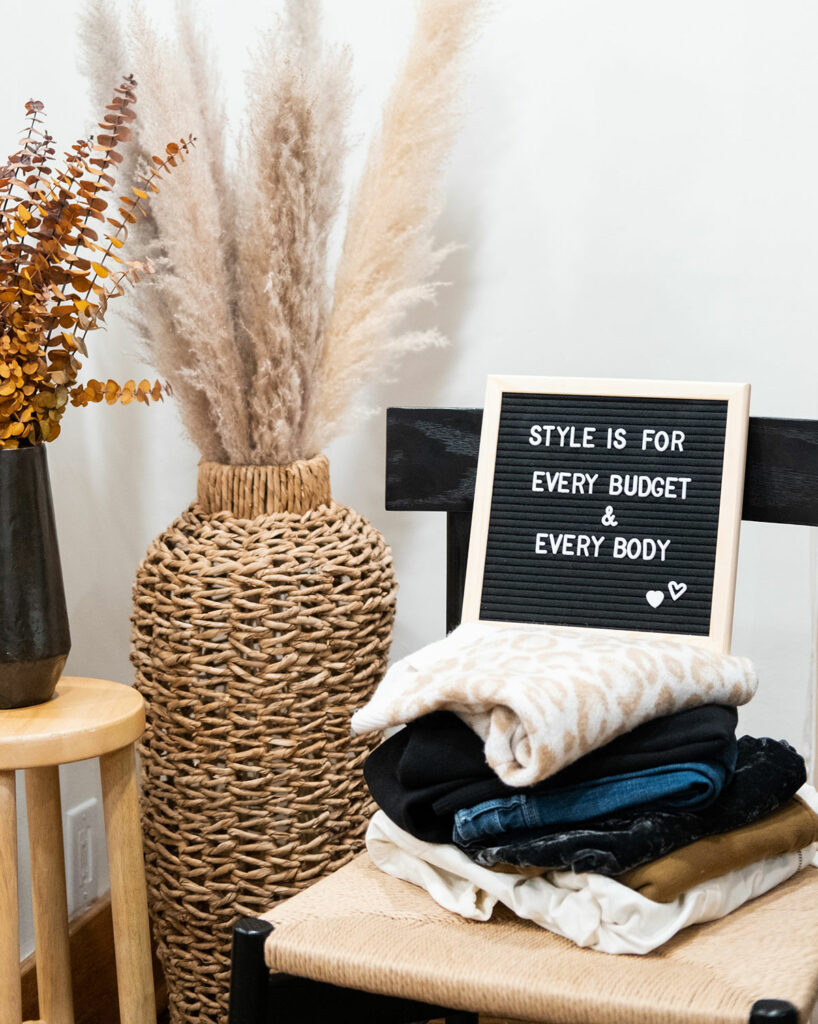 A pile of clothes folded on a chair with a sign that says style is for every budget and every body.